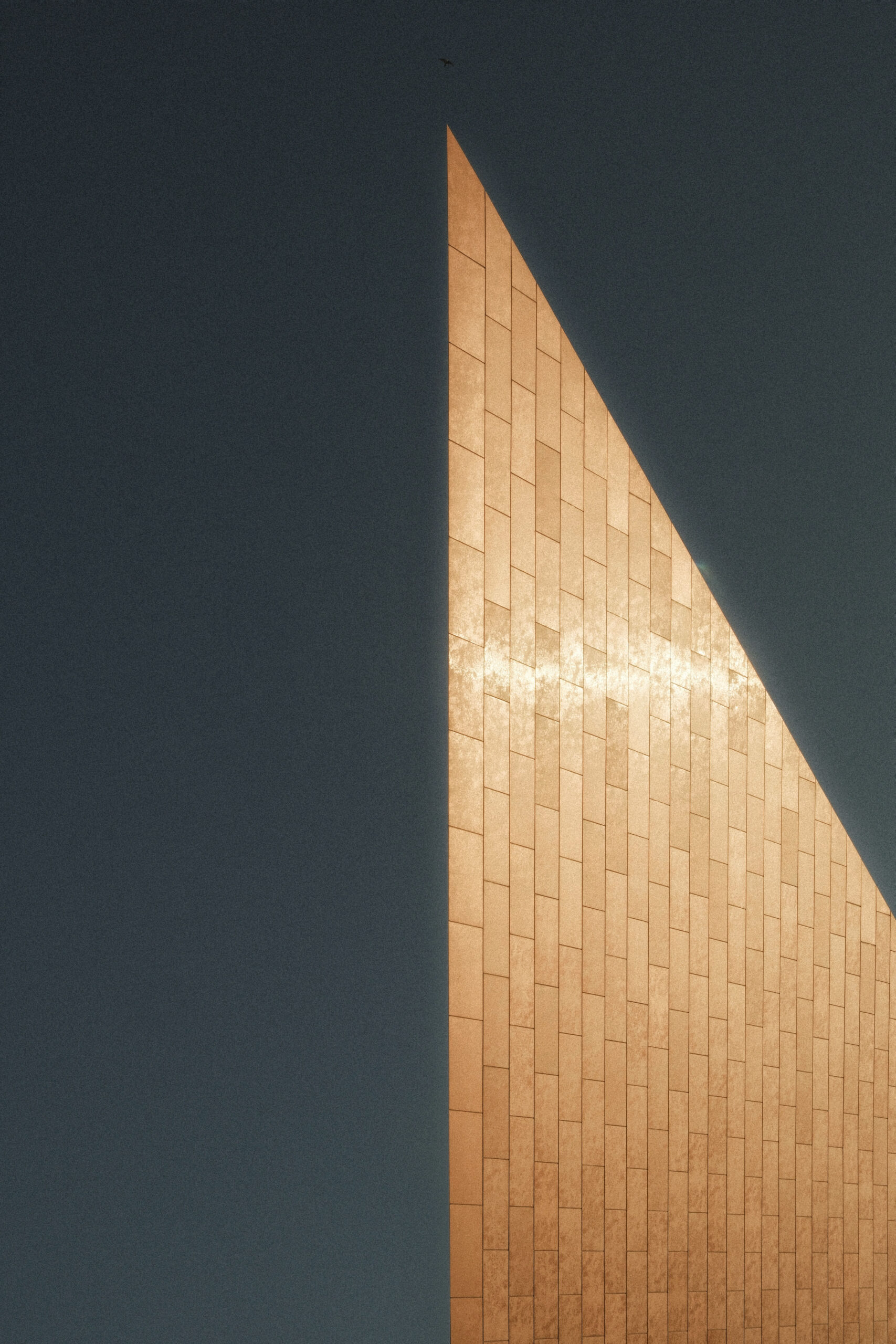 fotografia minimalista di dettaglio architettonico con grande parete inclinata illuminata dalla luce dorata laura farina fotografa