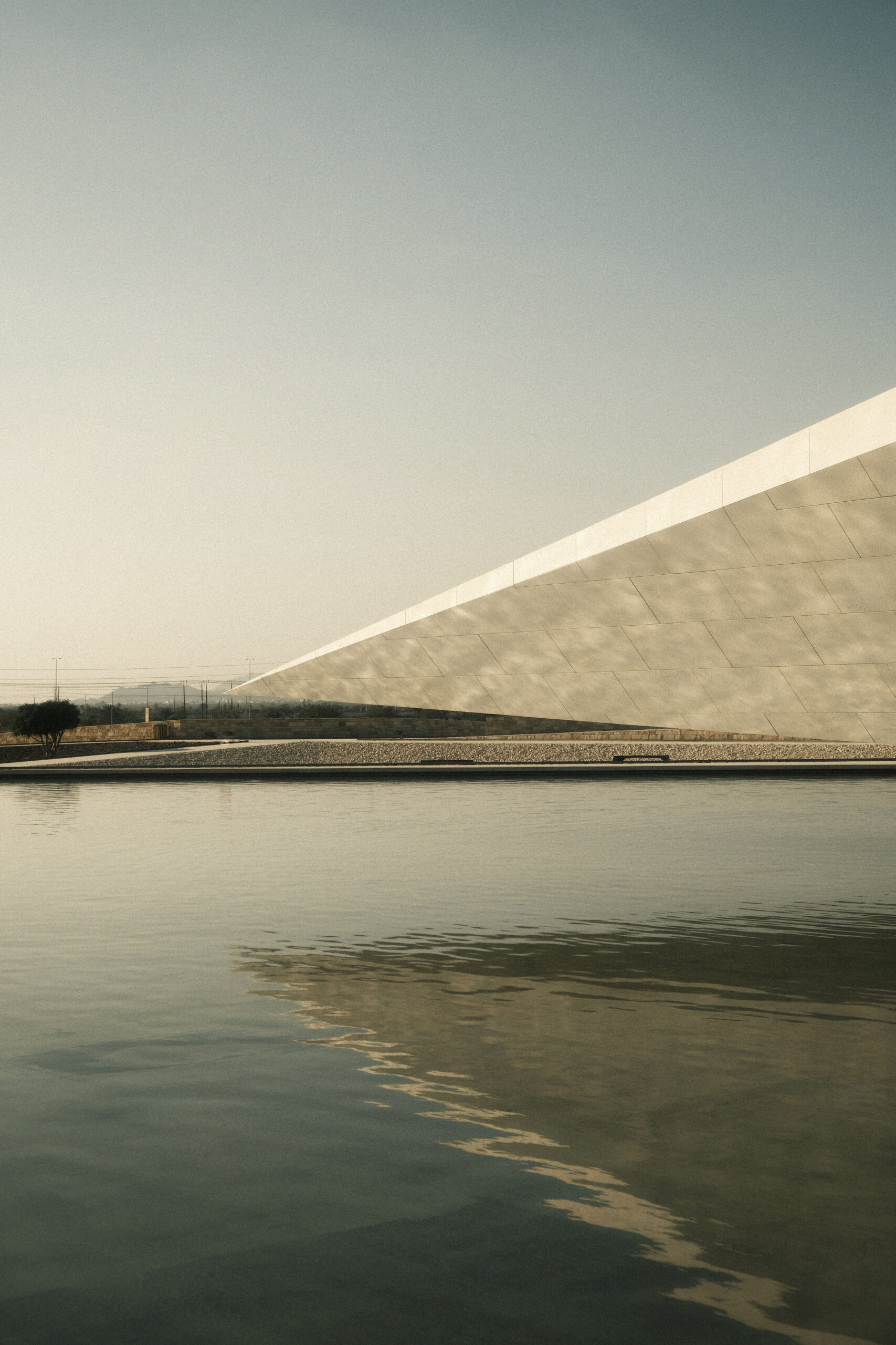 fotografia minimalista di architettura contemporanea con linea inclinata e riflesso sull’acqua al tramonto laura farina fotografa