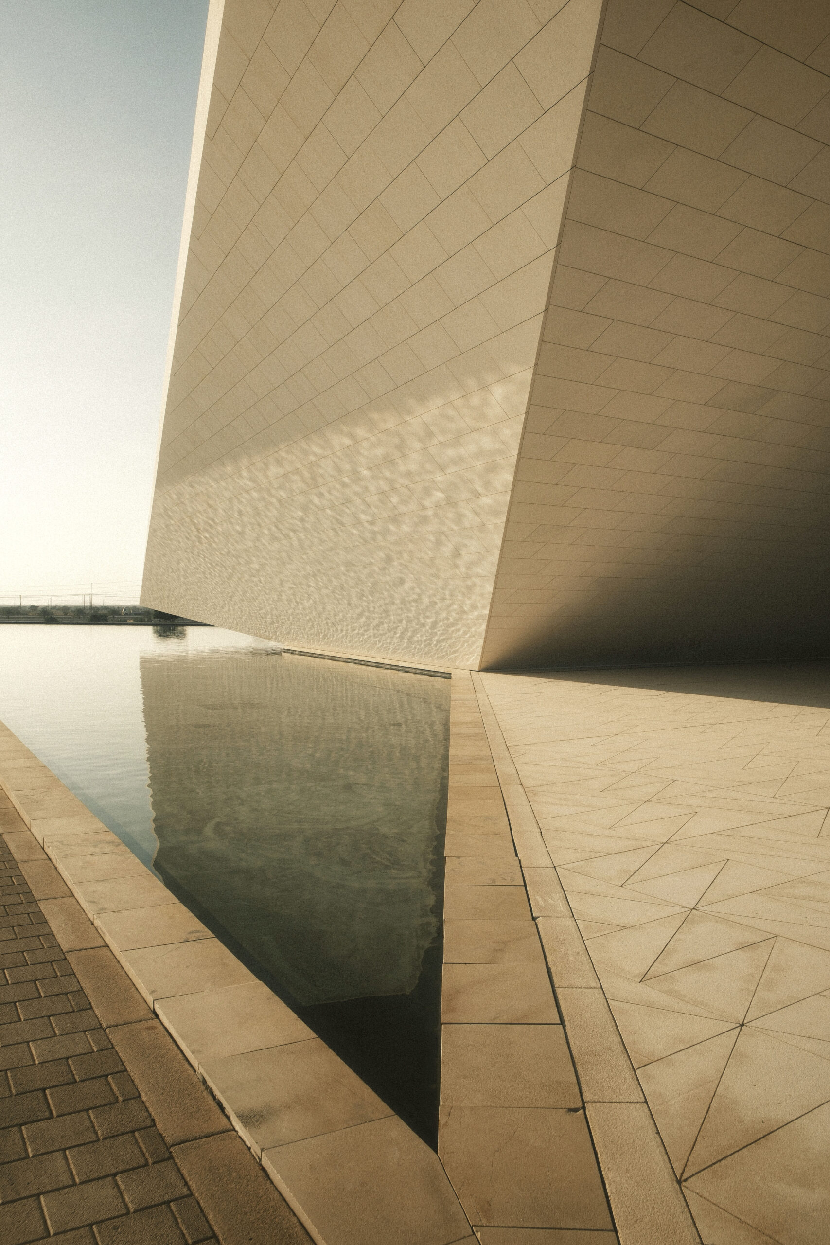 fotografia minimalista di architettura con grande volume inclinato e riflesso triangolare sull’acqua al tramonto laura farina fotografa