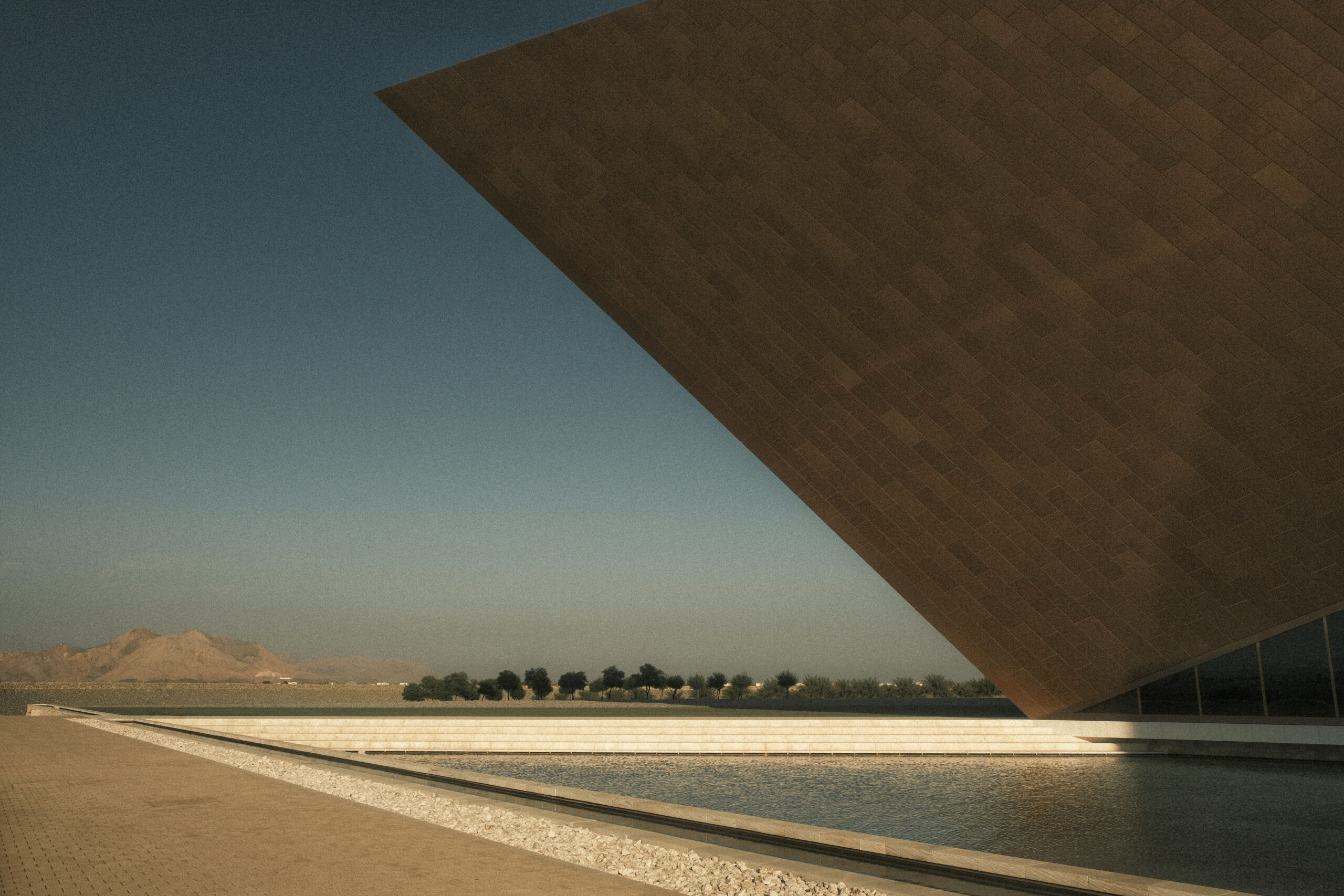 fotografia di architettura minimalista monumentale con grande volume inclinato e vasca d’acqua nel paesaggio desertico al tramonto laura farina fotografa