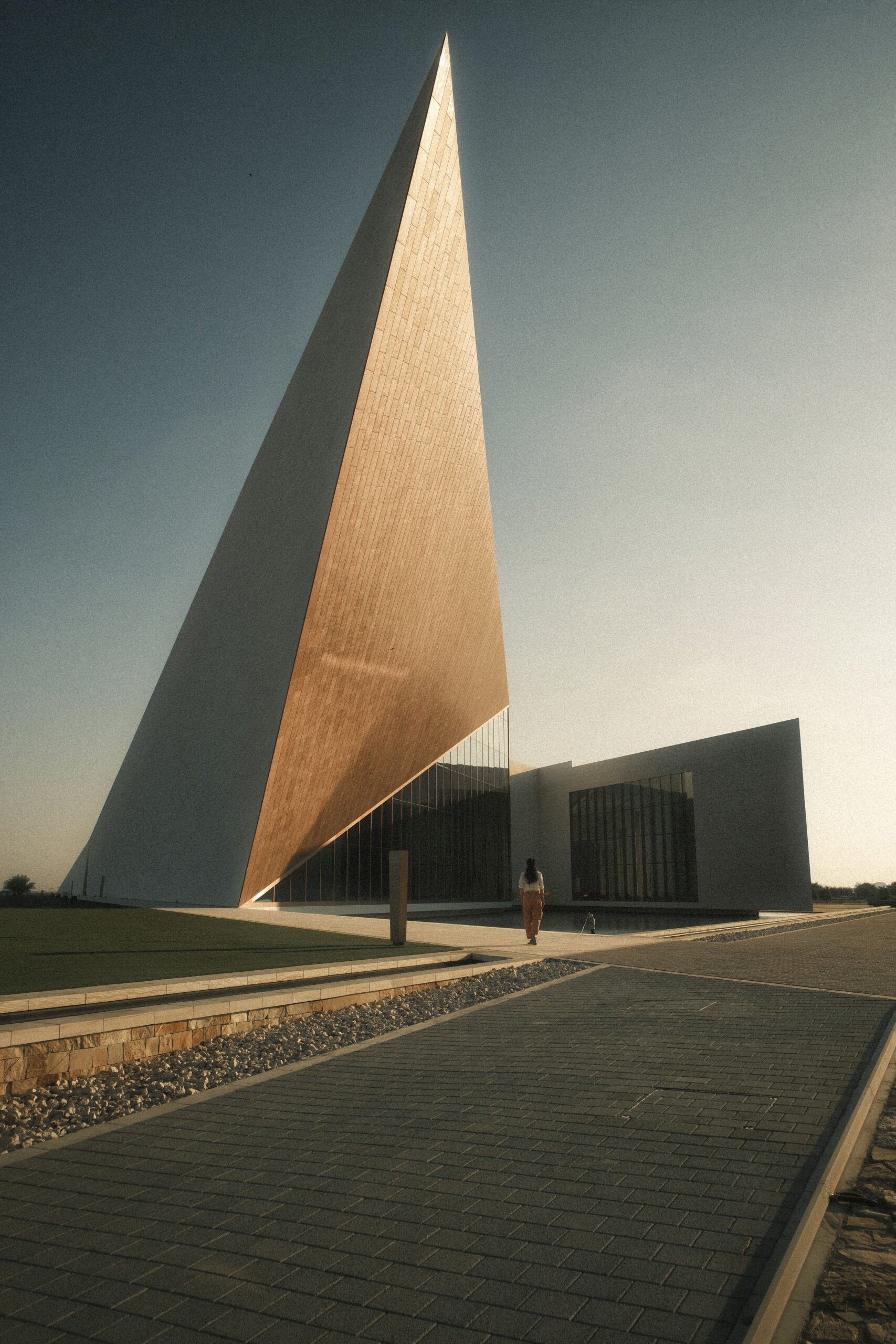 fotografia di architettura monumentale minimalista con grande volume inclinato e persona in scala nel paesaggio desertico al tramonto laura farina fotografa